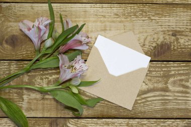 Yazmak için alanı olan basit küçük bir zarf ve ahşap zemin üzerinde küçük sevimli bir gül. Kalem yakın odaklama hattı dar, alan yüksek açılı görünümü sığ derinliği var.