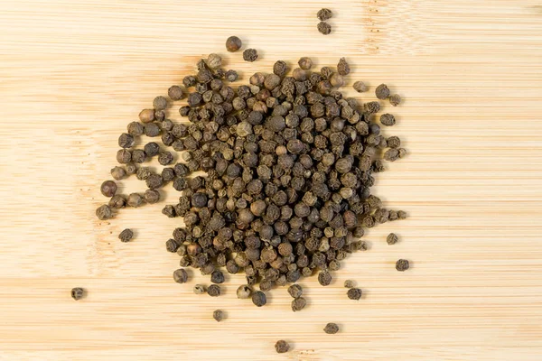 Pile Black Peppercorns Black Pepper Suszone Nasiona Bambusa Drewniane Tło — Zdjęcie stockowe