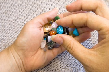 Kadınların elinde yarı değerli Gemstone koleksiyonu. Bulanık gri örülmüş arka plan. Üst görüş kapalı.