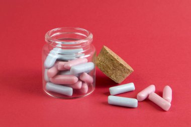 Kavanoz dolusu mavi ve pembe şeker parlak kırmızı arka plana karşı yakın plan