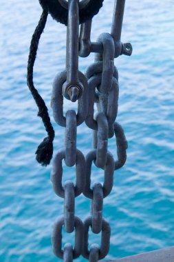 Gemi demirli iken paslı gri deniz zinciri yüzeyde ışık paslanıyor.