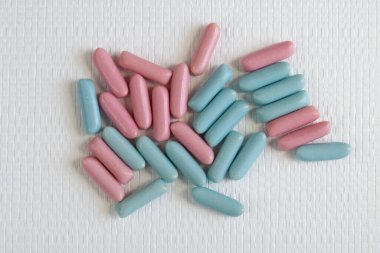 Beyaz desenli arka plan görünümüne dağılmış parlak mavi ve pembe renkli şekerler