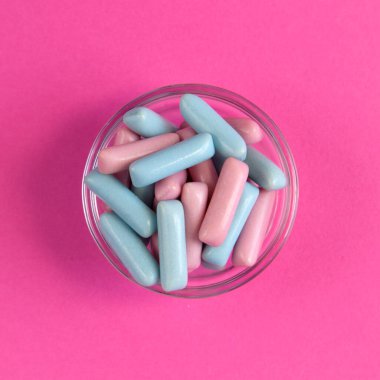 Parlak mavi ve pembe renkli şekerler parlak pembe arka plan görünümüne saçılmış.