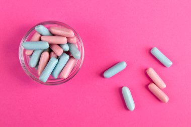 Parlak mavi ve pembe renkli şekerler parlak pembe arka plan görünümüne saçılmış.