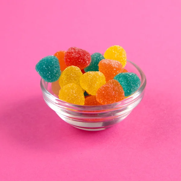 Bright colorful jelly candies in sugar on bright pink background close up