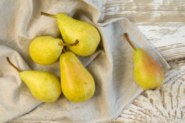 Kaba ahşap arka planda kahverengi kasede yeşil armutlar.