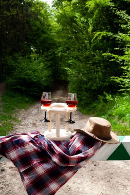 Bariyerde bir çift şarap kadehi ve kovboy şapkası. Doğada piknik.