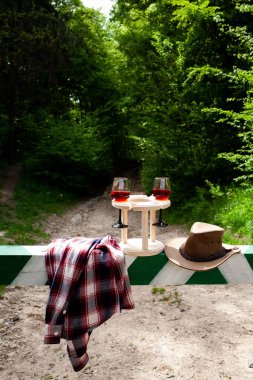 Bariyerde bir çift şarap kadehi ve kovboy şapkası. Doğada piknik.