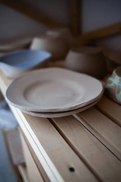 Stos ręcznie robione niebieskie miski ceramiczne i drewniane łyżki na prosty drewniany stół z niebieskim malowane drewniane ściany. — Zdjęcie stockowe