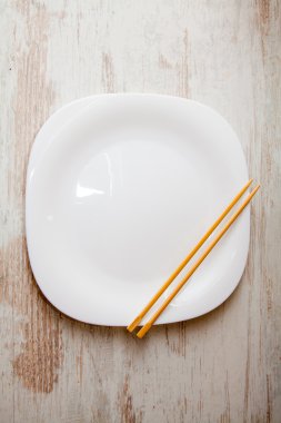 ahşap arka plan, yemek çubukları ile beyaz plaka üzerinde çeşitli suşi