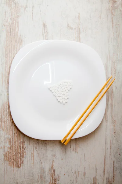 Pílula branca e pauzinhos em um prato — Fotografia de Stock