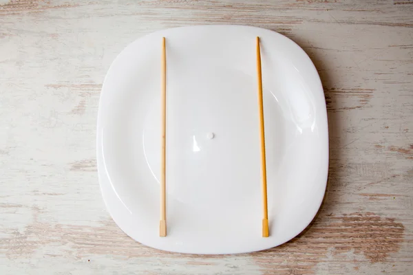 White pill and chopsticks on a plate — Stock Photo, Image