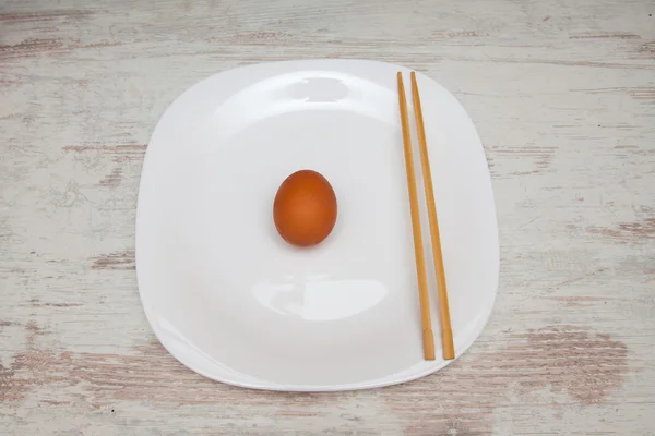 Ei met stokjes op een plaat duikt met houten achtergrond — Stockfoto