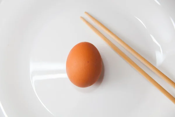 Uovo con bacchette su un piatto su fondo di legno — Foto Stock