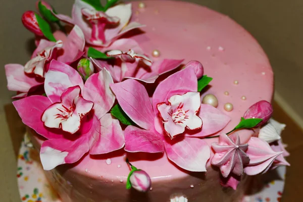 Světle růžový dort zdobený jedlými květy. Mastické různých barev, rozptýlené perly. — Stock fotografie