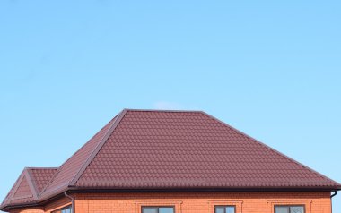 Bir evin çatı metal levha. Evin gables, windows ve metal çatı, taşma ve kar koruma ile donatılmıştır.