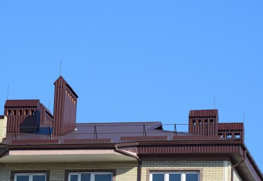 Çok öykülü bir binanın çatı. Saclar, taşma ve egzoz boruları ile donatılmış çatısı