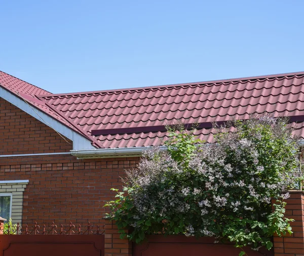 Gevel van een bakstenen gebouw met een dak gemaakt van bruin metaal. — Stockfoto