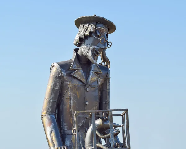 Statue of a furrier from metal with a rat in a cage. Metal statue.