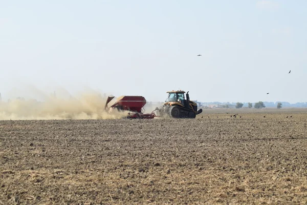 Traktor jedzie na polu i sprawia, że nawóz do gleby. Nawozy po orze pole. — Zdjęcie stockowe