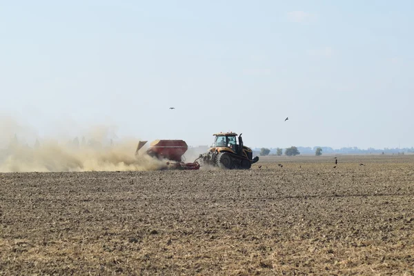 Traktor jedzie na polu i sprawia, że nawóz do gleby. Nawozy po orze pole. — Zdjęcie stockowe
