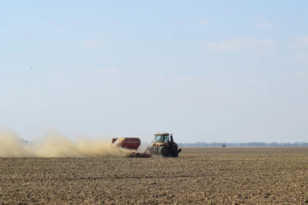 Trattore cavalca sul campo e rende il fertilizzante nel terreno. Fertilizzanti dopo l'aratura del campo . — Foto Stock