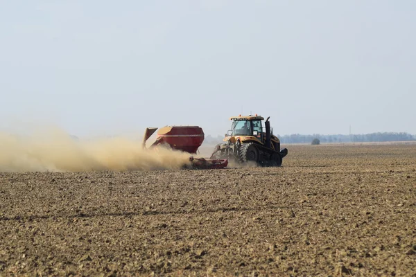 Traktor jedzie na polu i sprawia, że nawóz do gleby. Nawozy po orze pole. — Zdjęcie stockowe