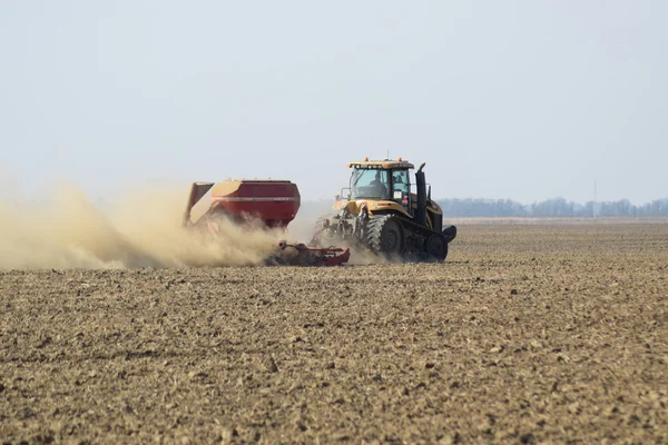 Traktor rider på fältet och gör gödselmedlet i marken. Gödselmedel efter plöjning fältet. — Stockfoto