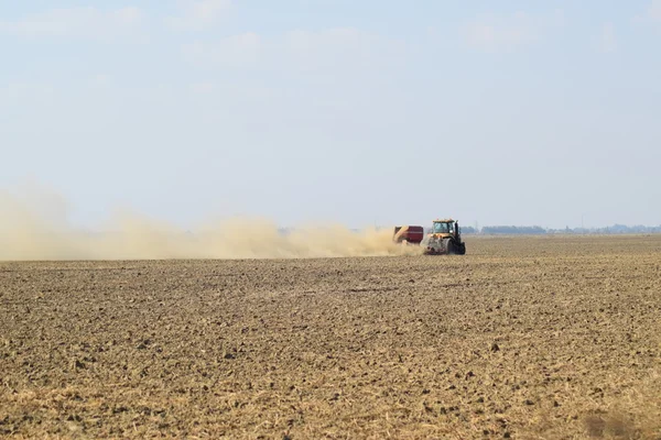 Трактор їде на полі і робить добрива в ґрунт. Добрива після оранки поля . — стокове фото