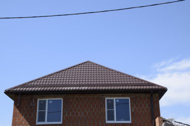 Bir evin çatı metal levha. Evin gables, windows ve metal çatı, taşma ve kar koruma ile donatılmıştır.