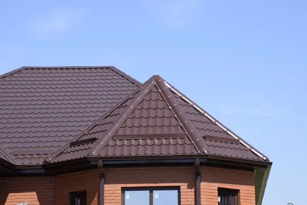 Bir evin çatı metal levha. Evin gables, windows ve metal çatı, taşma ve kar koruma ile donatılmıştır.