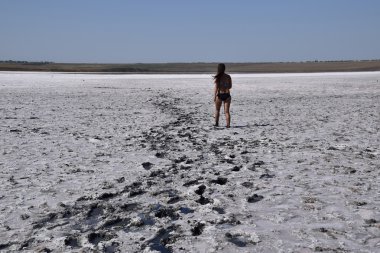 Tuz Gölü, dikiz kuru dipte yürüyen kadın. Esmer kadın mayoyla tuz ve çamur ile kuru bir gölün dibinde yürümek. Antik kurumuş göl.