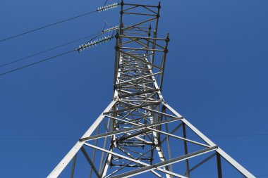 Yüksek gerilim hatları ve mavi gökyüzünde cirrus bulutlar ile düz ve yeşil tarım peyzaj güneşli bir güç pilonlar.