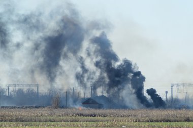 Fire on irrigation canals. Burning dry grass and cane fields in irrigation system. Burning debris and rubber clipart