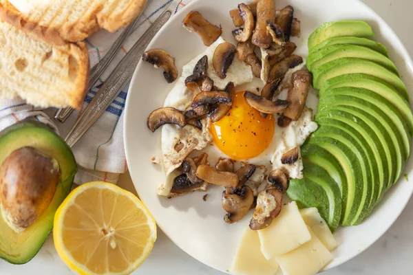 sliced avocado and egg with mushrooms toasted bread, lemon for healthy breakfast or snack. Top view.