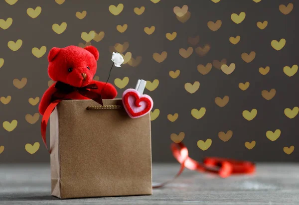 Image de vacances créative d'un ours en peluche assis dans un sac à provisions. Coffret cadeau, symbole du cœur et lumières de fées sur un fond. Concept de Saint-Valentin — Photo