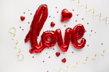 Kırmızı Hava Balonları beyaz arka planda, konfeti ve altın kurdeleli aşk sözcüğü şeklinde. Aşk konsepti. Tatil, kutlama. Sevgililer Günü ya da düğün, bekarlığa veda partisi dekorasyonu.