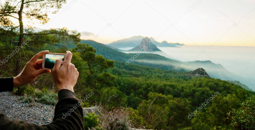 man hands making photos on his phone of beautiful mountain and sea view in fog and sunset Cyprus