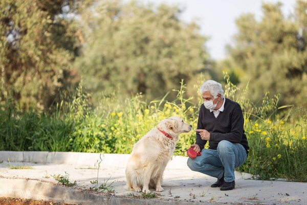 пожилой человек в маске со своей собакой на улице из-за загрязнения воздуха и эпидемии в городе. Защита от вируса, инфекции.Концепция взаимоотношений с животными во время карантина 2021