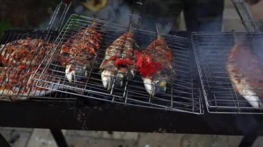 Dorado balığı kömürün üstünde ızgara yapıyor. Izgara tabağında aromatik baharatlarla deniz ürünleri pişiren yakın çekim. Kızartma, marine edilmiş leziz deniz ürünleri. Kıbrıs 'ta yaz bahçesinde barbekü