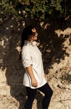 Güneşe bakan genç bir kadın, kapalı gözler, doğal mauntain taşından arka planda hayatın tadını çıkar. Yüzünde sert gölgeler vardı. Sonbahar dönemi konsepti, kendi kendine özgürlük, estetik.
