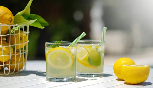 Erfrischender Mojito oder Limonade im Glas. Sommergelber Fruchtcocktail auf weißem Tisch. Hartes Licht, harte Schatten: Sommerferienkonzept. Ansicht von oben. Trend 2021 — Stockfoto