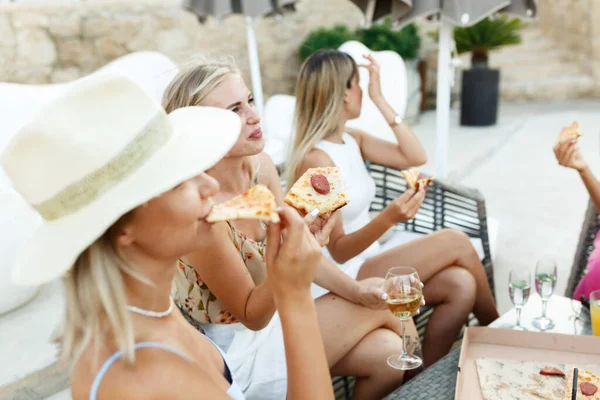 Multiracial friends girls hanging out with drinks,eating pizza together, diverse millennial people sharing pub cafe pizzeria table, smiling students chatting having fun hanging out in public place.