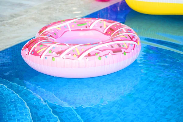 Летние каникулы. Расслабься у бассейна. Надувное кольцо, розовый пончик — стоковое фото