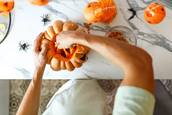Um close-up de mão de homem puxa sementes e material fibroso de uma abóbora antes de esculpir para Halloween. Jack-o-lanterna. — Fotografia de Stock