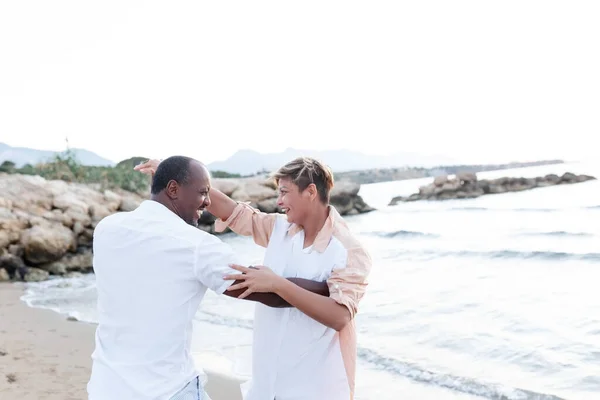 Casal sorrindo de raça mista desfrutando de férias, turista se divertindo andando à beira-mar, diversidade e conceito de amor — Fotografia de Stock