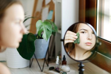 Yetişkin beyaz kadının portresi, doğal Gua sha Yeşim Taşı Roller 'ı kullanarak gün içinde evde yüz masajı yapıyor. Kozmetik ve güzellik hizmetleri ön manzara fotokopi alanı