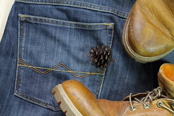 Conos de pino y botas sobre fondo jaens  . —  Fotos de Stock