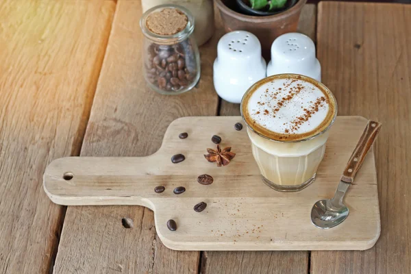 Xícara de café de cappuccino e grãos de café na mesa de madeira .effect borrão estilo vintage e ruído — Fotografia de Stock