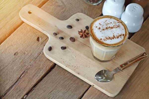 Kaffekopp med cappuccino og kaffebønner på bordet av tre, årgang og støy – stockfoto